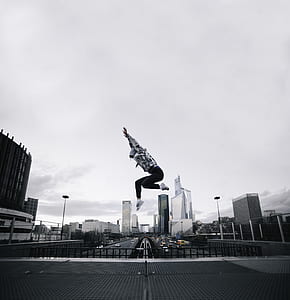 person wearing hoodie jumping on building photography thumbnail