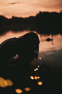 Silhouette of Woman Near Body of Water during Golden Hour thumbnail
