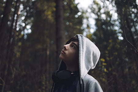 boy's looking up surrounded by trees during daytime thumbnail