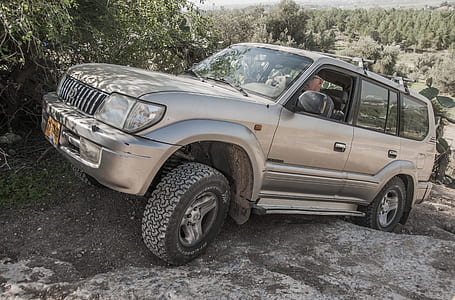 person driving beige SUV on rough gray terrain thumbnail