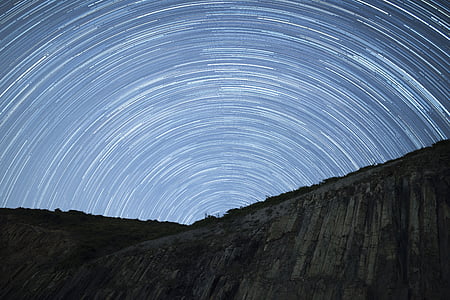 timelapse photography of green and grey mountain under sky with stars thumbnail