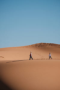 girl and boy walking on desert under blue sky thumbnail