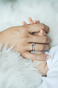 person wearing ring holding baby's hand thumbnail