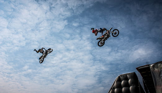 two man riding motocross bikes while doing tricks in mid-air thumbnail