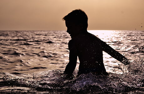 silhouette of boy swimming during sunset thumbnail