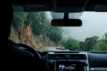 person driving vehicle on road beside mountain thumbnail
