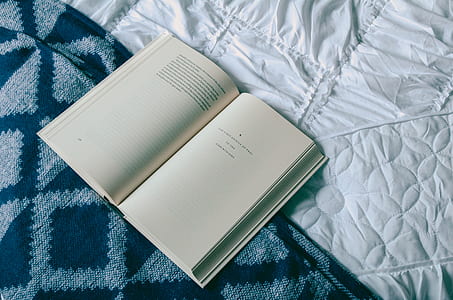 opened book on blue and white textile thumbnail