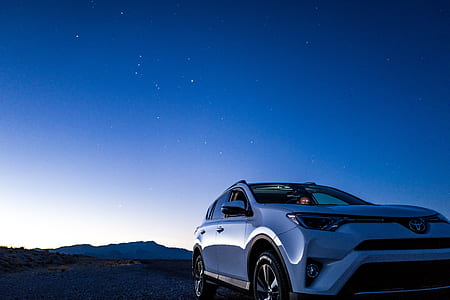 gray Toyota car at the field with mountain at the distance during night thumbnail