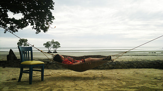 woman lying on brown wicker hammock thumbnail