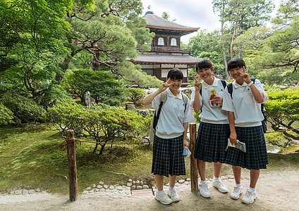 photo of three school girls standing in front of trees near pagoda thumbnail