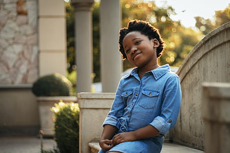 toddler in blue denim coat sitting on bench thumbnail