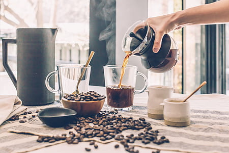 shallow focus photography of person pouring coffee on clear glass mug thumbnail