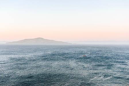 sea near island under gray sky thumbnail