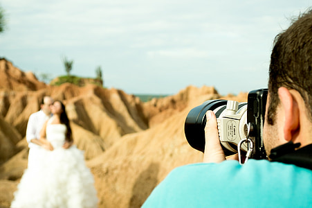 man taking picture bride and groom on brown mountain thumbnail