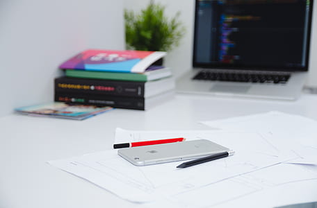 silver iPhone 6 between black and red ballpoint pen top of white printer paper thumbnail