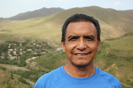 man wearing blue crew-neck shirt standing near mountain thumbnail