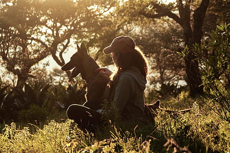 woman sitting beside her dog on grass field thumbnail