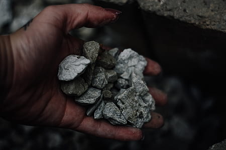 person grabbing gray stone fragments thumbnail