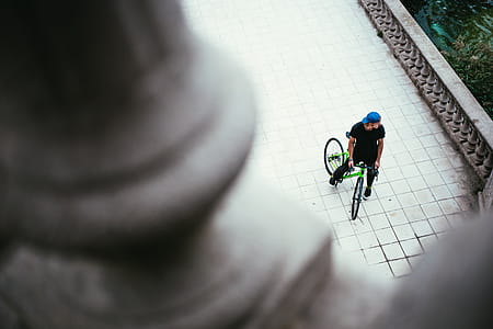 A young Caucasian male cyclist wearing blue cap halts on the street thumbnail