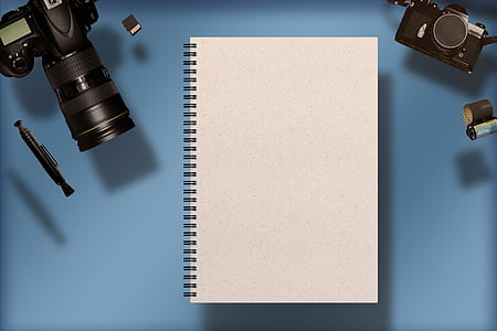 white spiral notebook beside black DSLR camera thumbnail