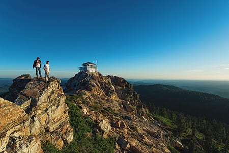 two persons standing on mountain near cliff thumbnail