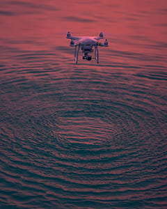 photography of quadcopter drone flying above body of water thumbnail