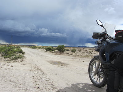 black motorcycle on sand near green plant during daytime thumbnail