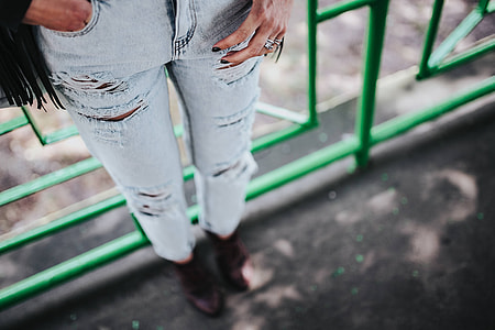 Blonde woman in a black jacket and ripped jeans by a green handrail thumbnail