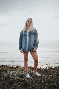 woman standing on grass near body of water thumbnail