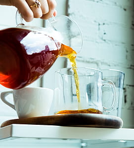 woman pouring tea on clear glass mug during daytime thumbnail