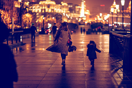 woman walking on street beside child at night thumbnail