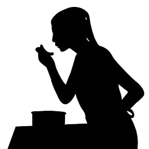 Silhouette of woman taking a bite of food. thumbnail