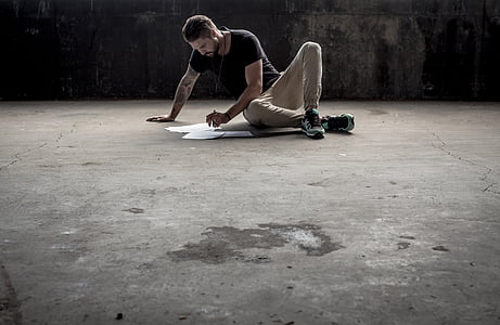 man and blue and brown clothes sitting on gray concrete pavement thumbnail