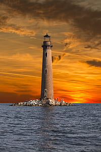 brown lighthouse surrounded by body of water thumbnail
