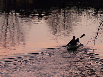 silhouette photo of person paddling boat on body of water thumbnail
