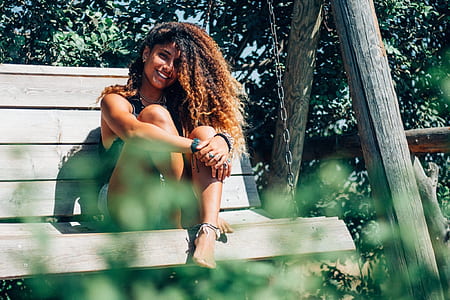 woman sitting on brown wooden swing bench thumbnail
