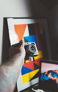 person holding gray and black SLR camera thumbnail