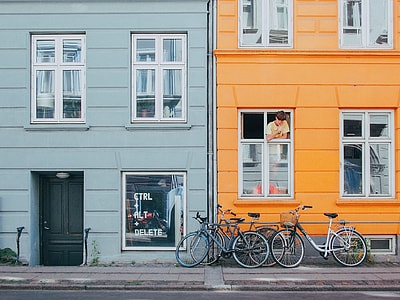 blue and yellow high rise building with bicycles on front and boy on window at daytime thumbnail