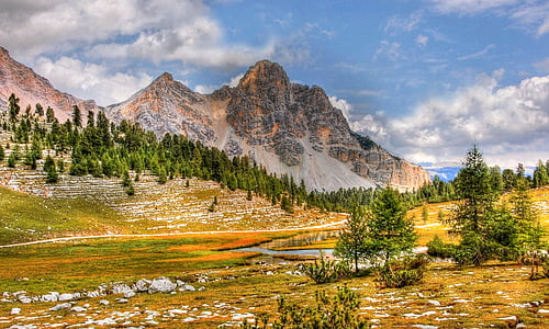 green trees near mountains under blue cloudy sky during daytime thumbnail