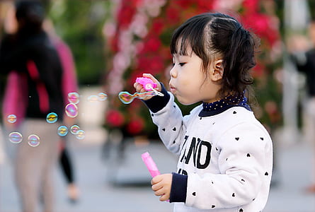 Toddler Girl Wearing White and Black Sweater Holding Plastic Bottle of Bubbles at Daytime thumbnail