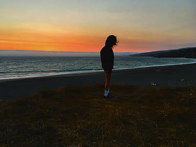Person Standing on Seashore during Sunset thumbnail