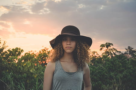 woman in gray tank top wearing black sun hat during sunset thumbnail