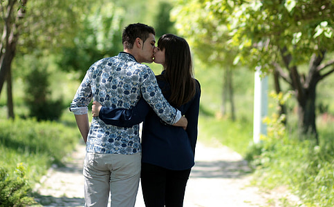 couple kissing each other between trees during daytime thumbnail