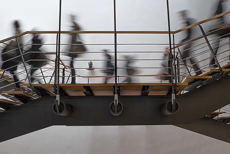 low angle of people walking on brown and gray staircase thumbnail