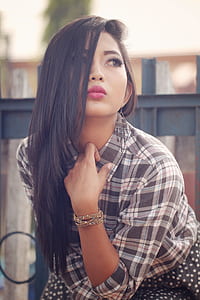 woman wearing gray and white plaid elbow-sleeved shirt holding her neck thumbnail