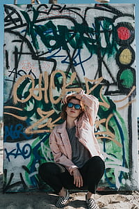 man squatting in front of graffiti wall at daytime thumbnail