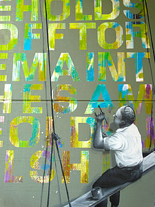 man sitting on board painting on wall thumbnail