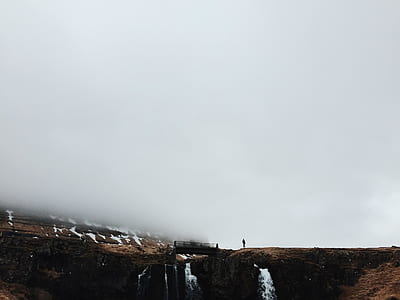 person standing near waterfalls thumbnail
