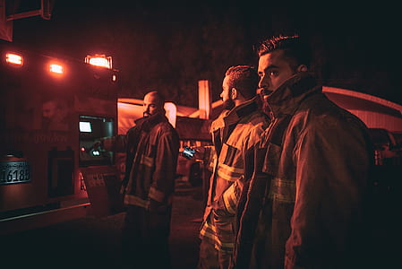 three man wearing bunker gear standing near vehicle truck at night thumbnail