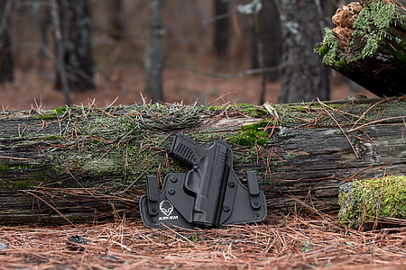 black pistol case leaning on tree log thumbnail
